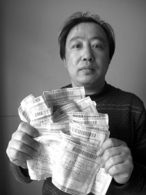 李龙拿着一摞诉状的快递回单。从2008年开始,他先后向法院递交了20余个行政案件的诉状。图/记者周喜丰