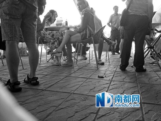 泰国一景区购物点外,中国游客围在一起等候,现场闹哄哄,地上散落着包装纸、烟头等杂物。
